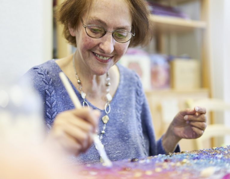 ältere Frau, beim Malen mit Pinsel
