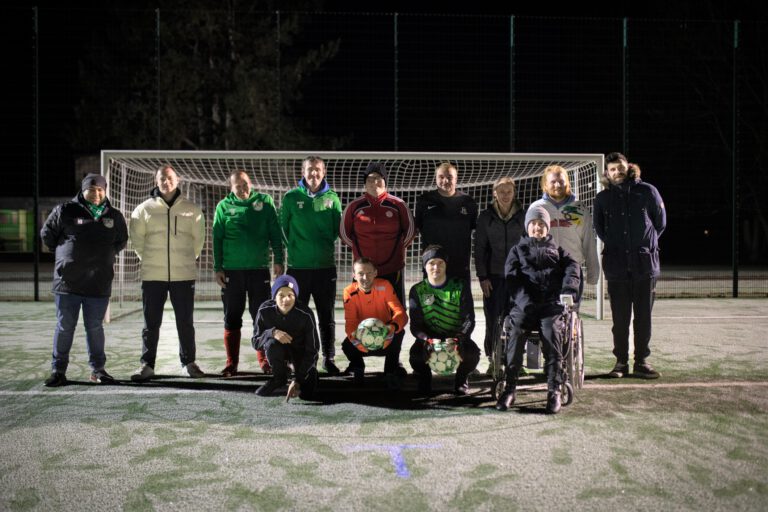 Gruppenbild einer inklusiven Fussballmannschaft auf einem winterlichen Fußballplatz